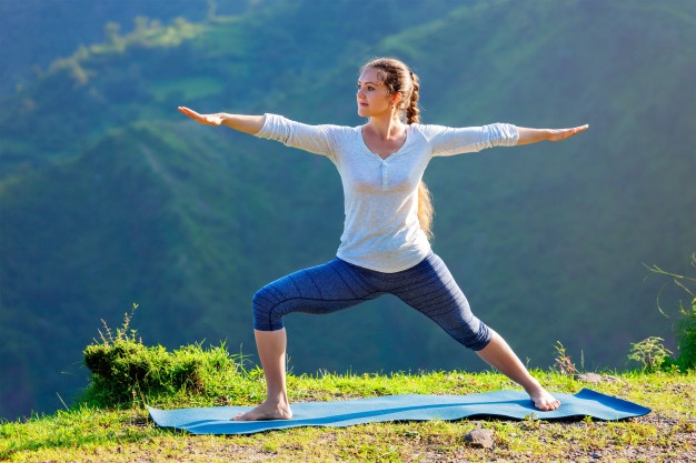 mulher-fazendo-yoga-asana-virabhadrasana-2-pose-de-guerreiro-ao-ar-livre_163782-4362